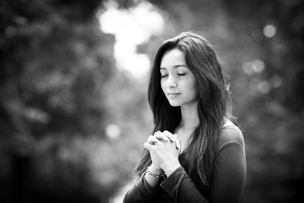 Woman hands praying with a blible in his legs Outdoors black and white