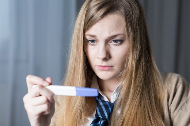 Stressed teenage girl looking on pregnancy test