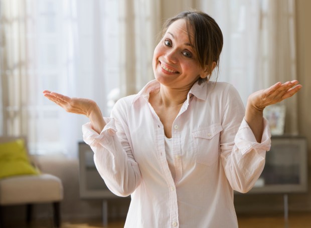 Beautiful caucasian woman shrugging with her hands up, looking sheepish. Horizontal view