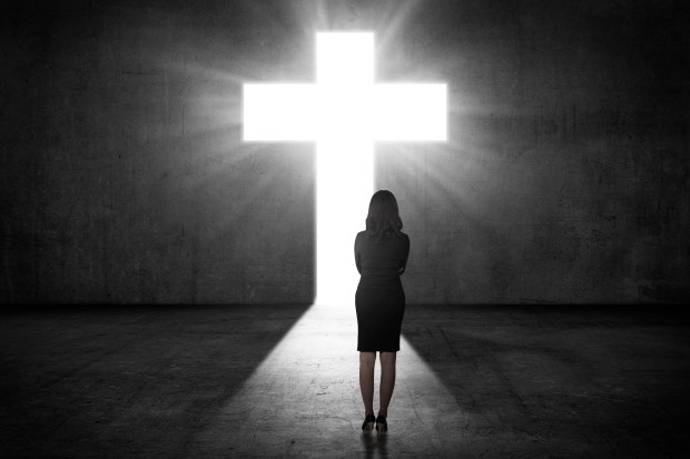 Business woman looking the shining cross on the wall